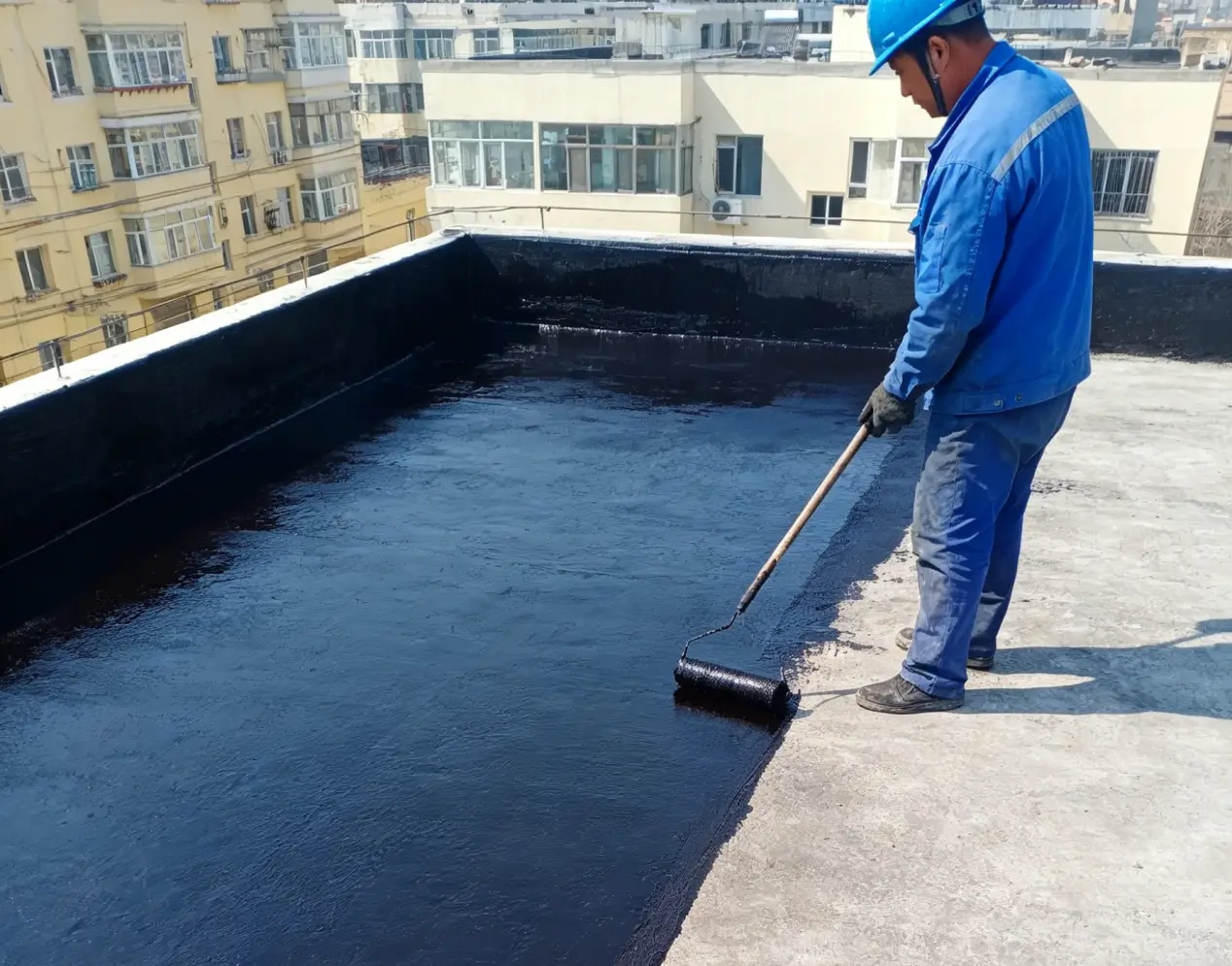 Worker applying liquid waterproofing coating with roller